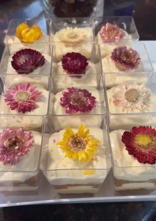 Mini layer cakes in clear containers with edible flower toppings