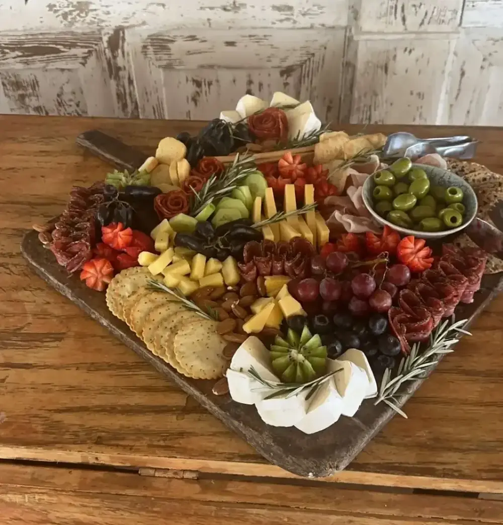 Wooden board filled with assorted meats, cheeses, and berries